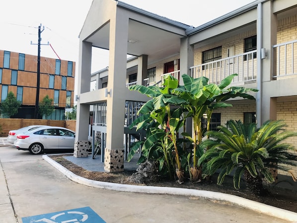 A modern building with a covered entrance, a parking area, and a wheelchair-accessible ramp. - Summit Inn - Houston Medical Center (Houston)