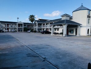 A parking lot with several cars, a building with a dome and a sign reading "3138", and a palm tree. - Summit Inn - Houston Medical Center (Houston)