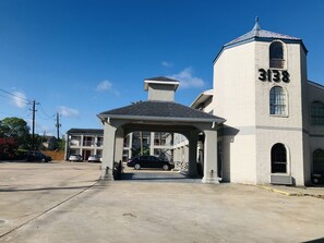 A building with a tower and a covered entrance. - Summit Inn - Houston Medical Center (Houston)