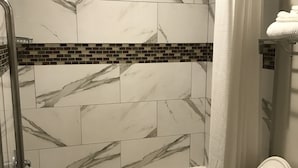 A bathroom with a bathtub, toilet, and shower area.