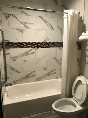 A bathroom with a bathtub, toilet, and shower area. - Summit Inn - Houston Medical Center (Houston)