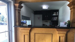 A reception area with a wooden counter, a fire alarm panel sign, and a potted plant. - Summit Inn - Houston Medical Center (Houston)