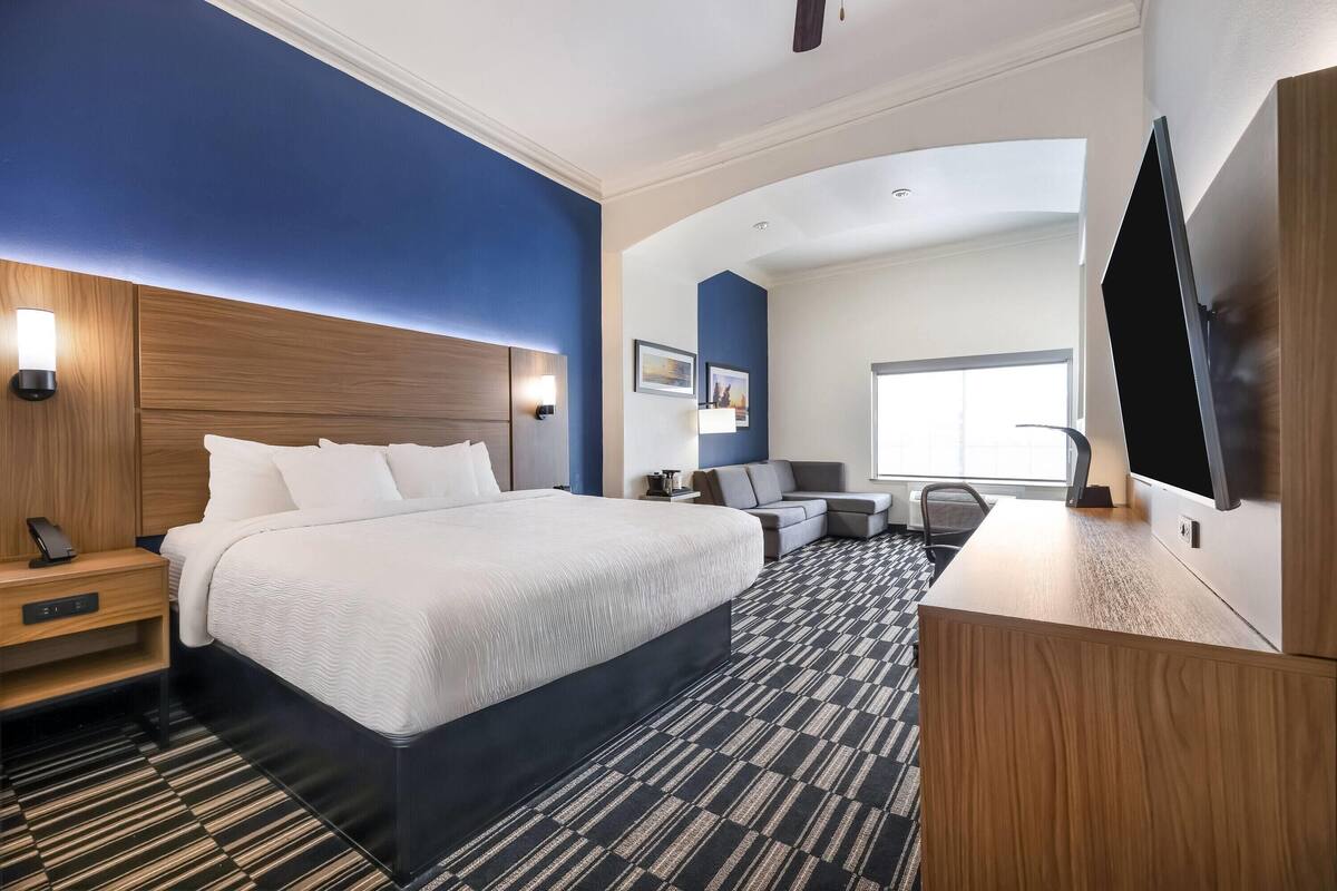 Ein Hotelzimmer mit einem großen Bett, einem Schreibtisch, einem Flachbildfernseher und einem Sofa.