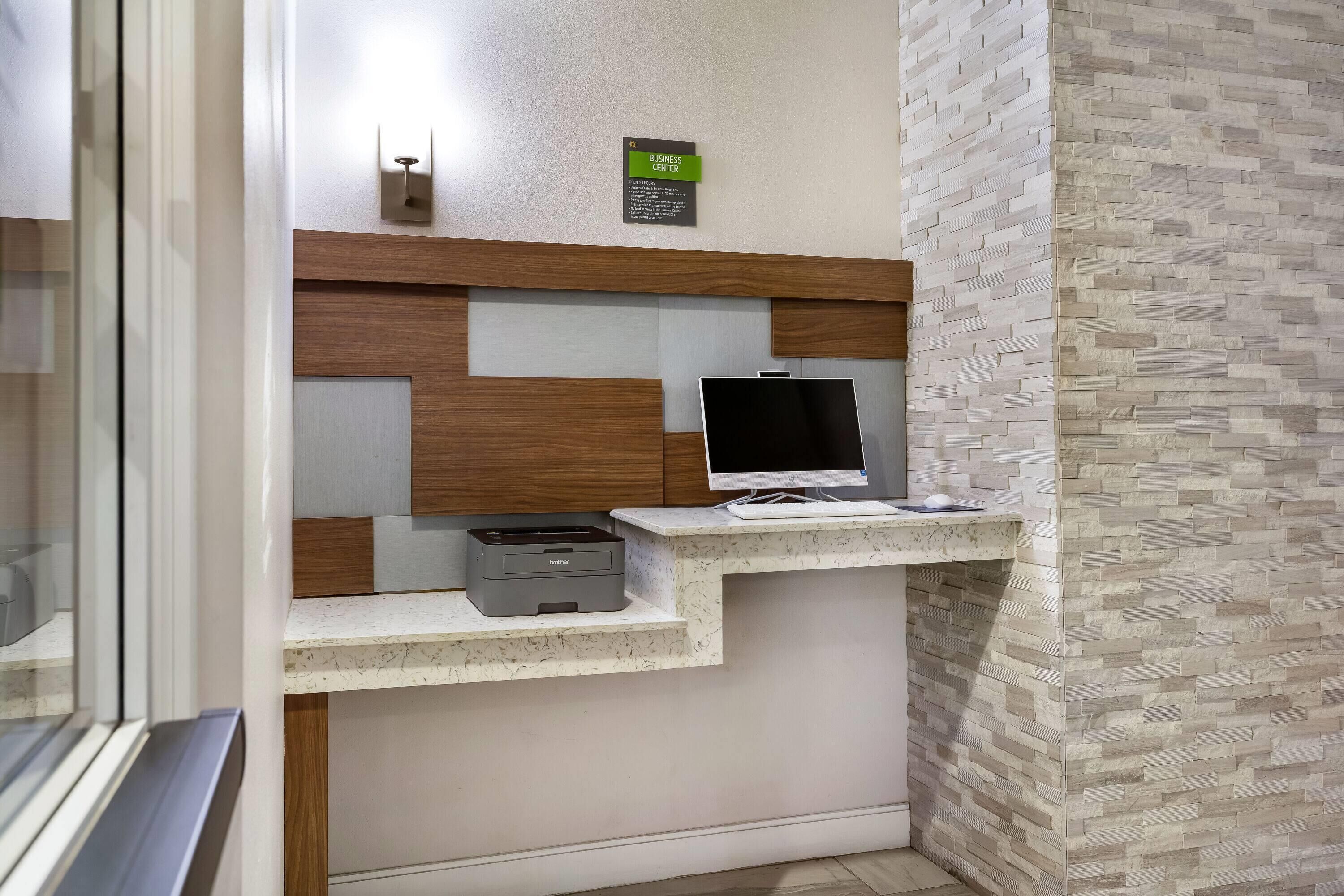 Un mostrador de recepción con computadora, impresora y un letrero que indica un centro de negocios.