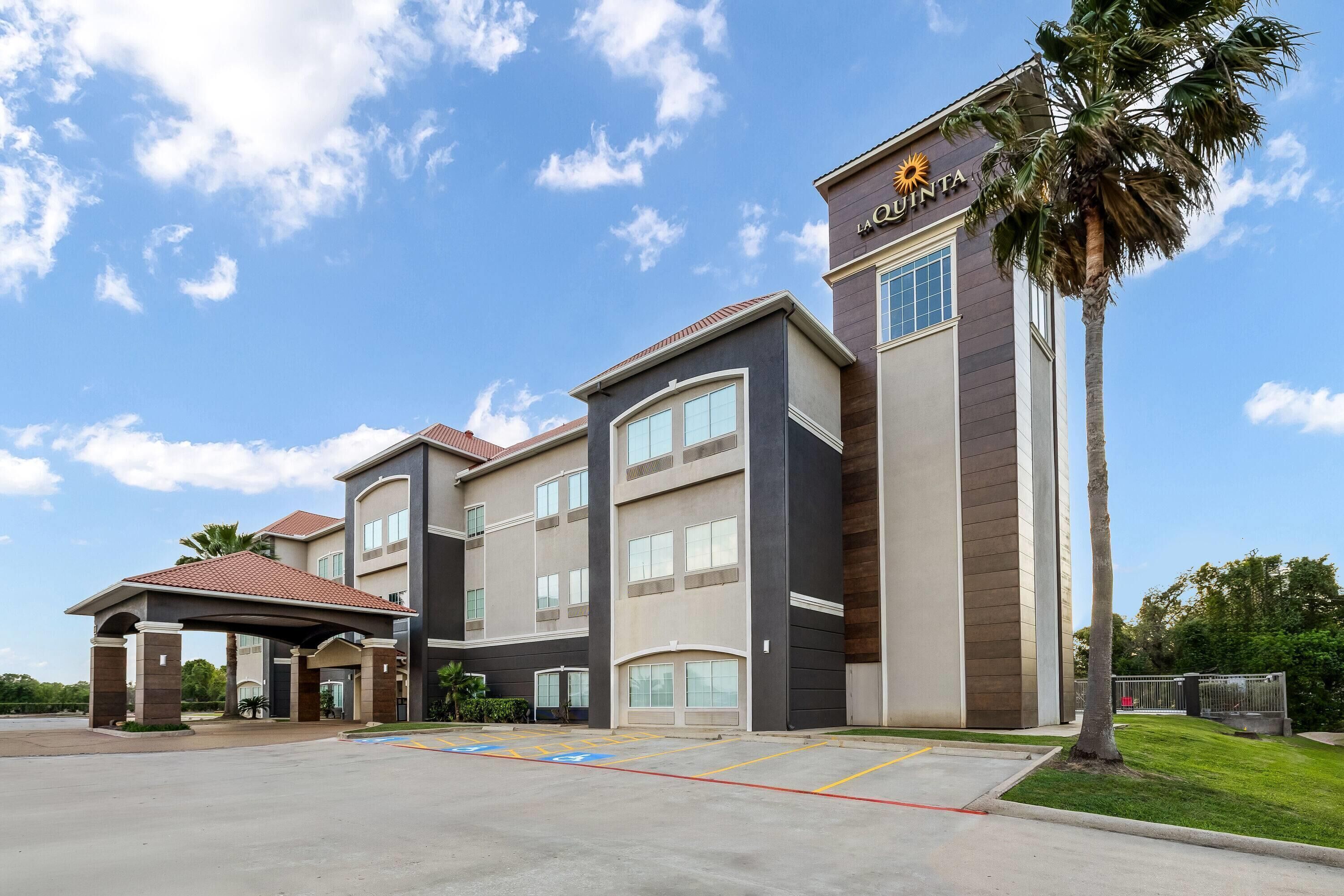 A hotel with a modern design, featuring a covered entrance, multiple floors, and a palm tree in the foreground.