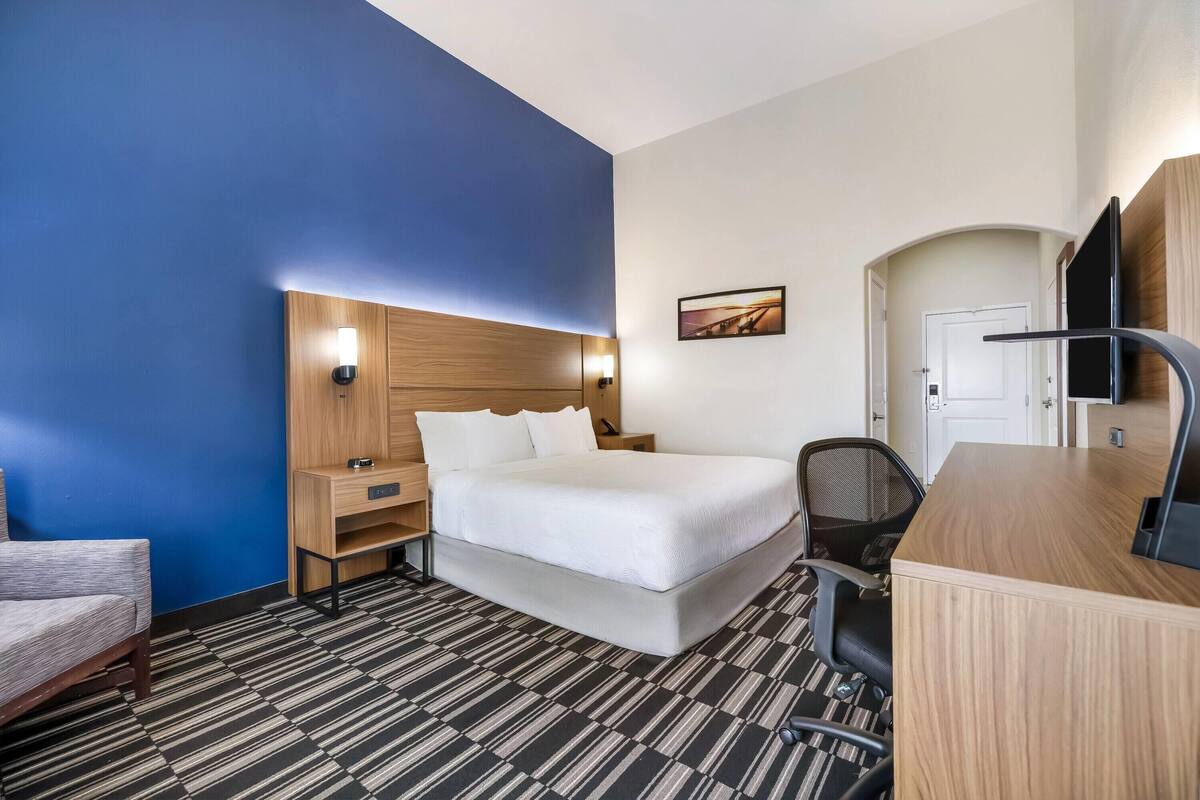Ein Hotelzimmer mit Bett, Schreibtisch, Stuhl und einem kleinen Tisch.