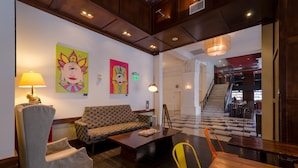 Un hall con sofá, sillones, una mesa de centro y obras de arte en las paredes.