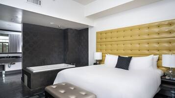 Relax in a spacious room with a large bed, separate bathtub, and comfortable bench.