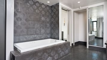A modern bathroom with a large bathtub, dark patterned tiles, and a sleek design.
