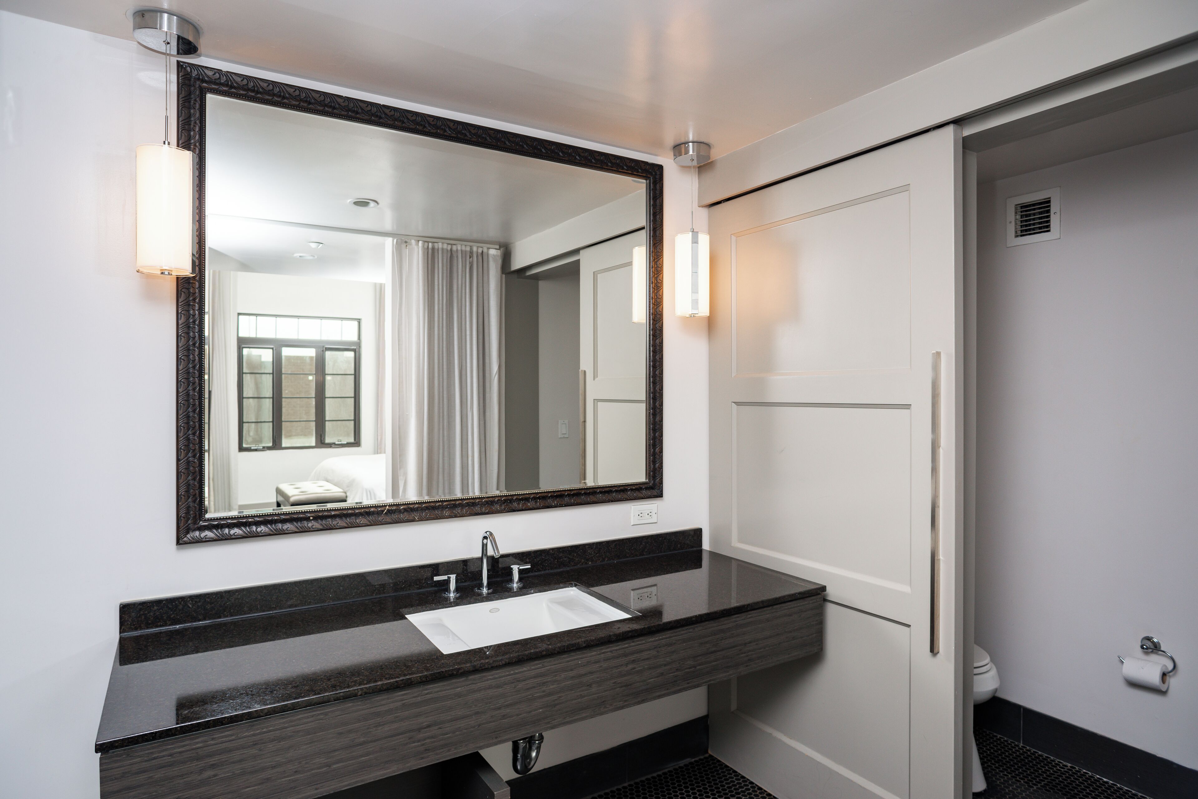 A modern bathroom with a large mirror, a sink, and a toilet.
