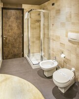 Un baño moderno con ducha envuelta en vidrio, un bidé y un inodoro.