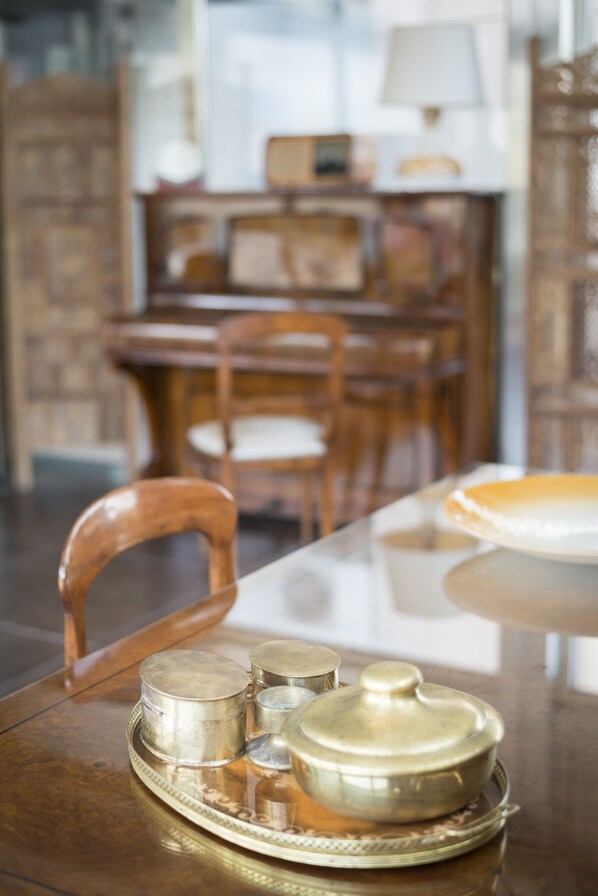A dining table with a tray of silverware and a covered pot.