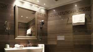 A modern bathroom with a large mirror, a sink, a toilet, and a bidet. - Rome Airport Hotel Fiumicino (Fiumicino)