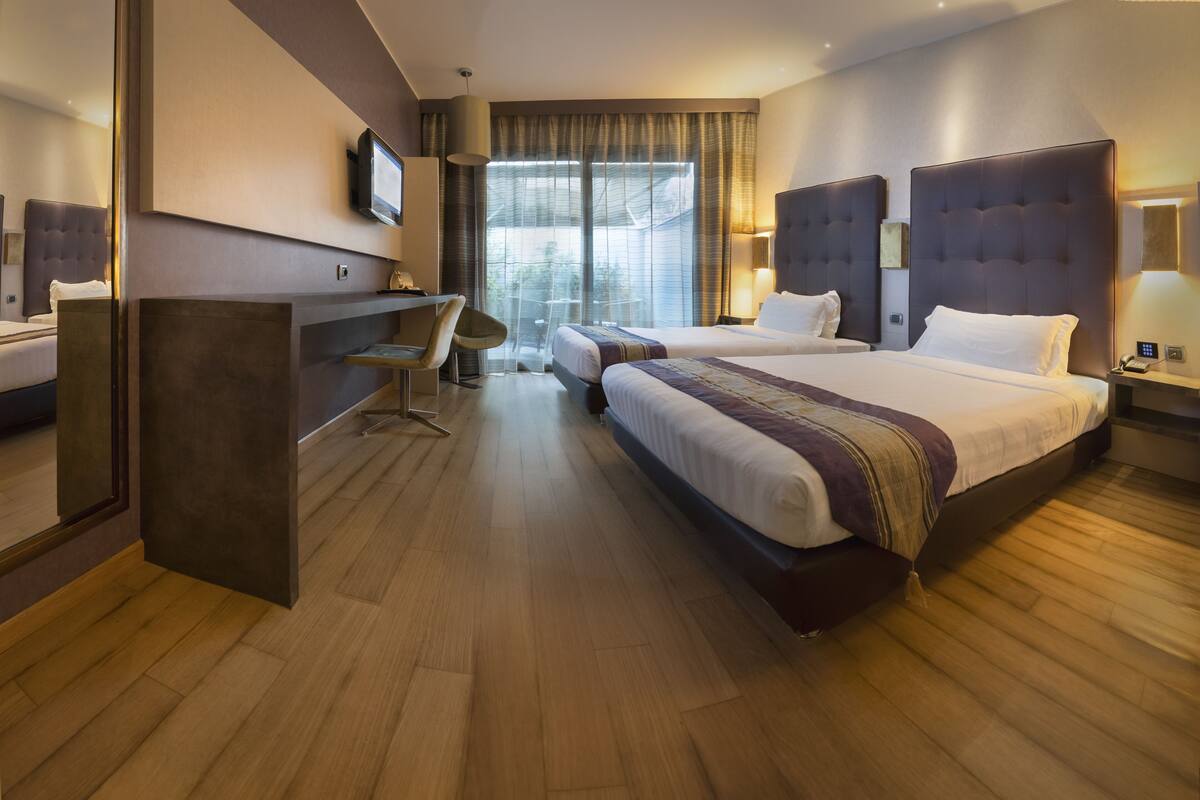 Habitación de hotel con una cama grande, un escritorio y un televisor.