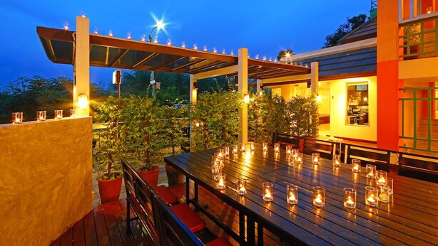 An outdoor dining area with a pergola, candles, and potted plants. - Floral Shire Resort (Bangkok)