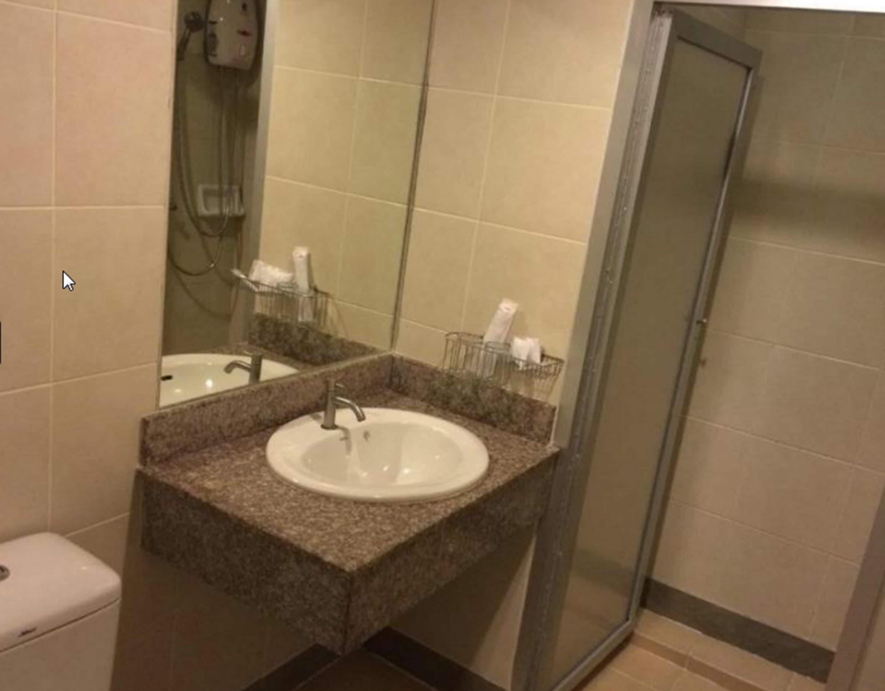 A bathroom with a sink, mirror, and shower.