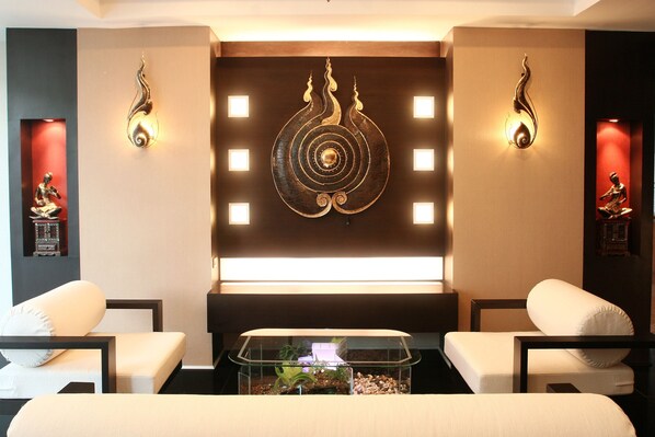 A modern room with two white sofas, a glass coffee table with decorative items, and wall-mounted light fixtures.