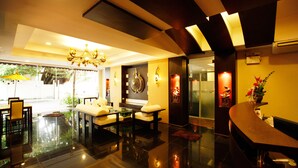 A modern lobby with a reception desk, seating area, and a chandelier. - Mirth Sathorn Hotel (Bangkok)
