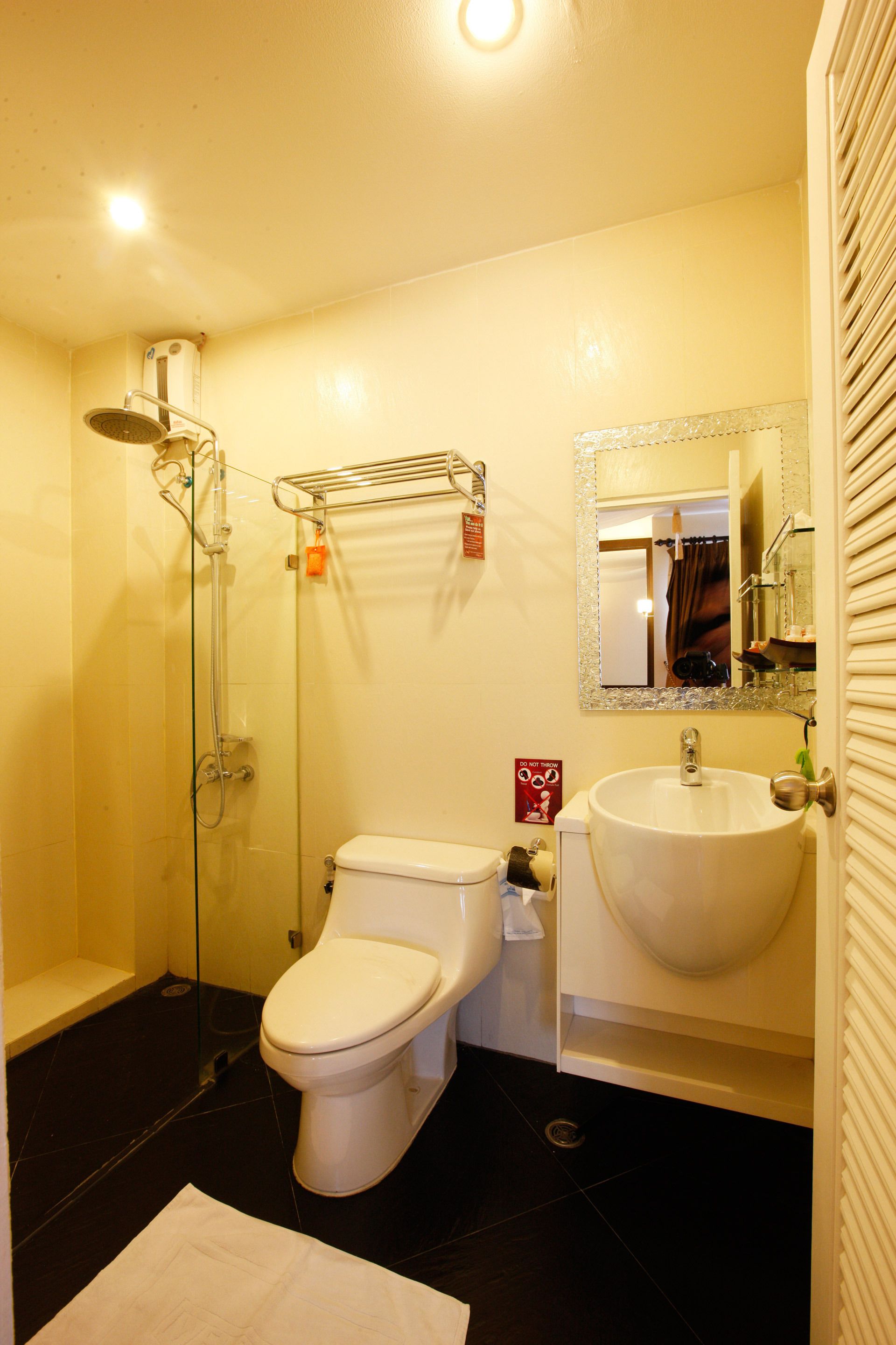 A bathroom with a toilet, sink, shower, and a mirror.