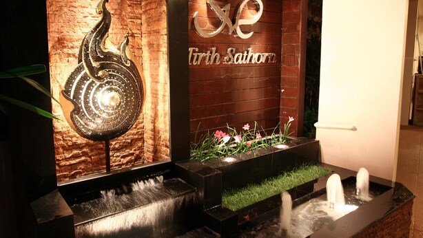 A water feature with a peacock sculpture and a sign reading "Tirth Sathon". - Mirth Sathorn Hotel (Bangkok)