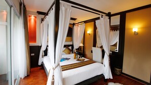 A four-poster bed with white linens, a wooden floor, and a mirror on the wall. - Mirth Sathorn Hotel (Bangkok)