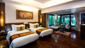 Habitación de hotel con dos camas, un área de comedor y vistas a zonas verdes.