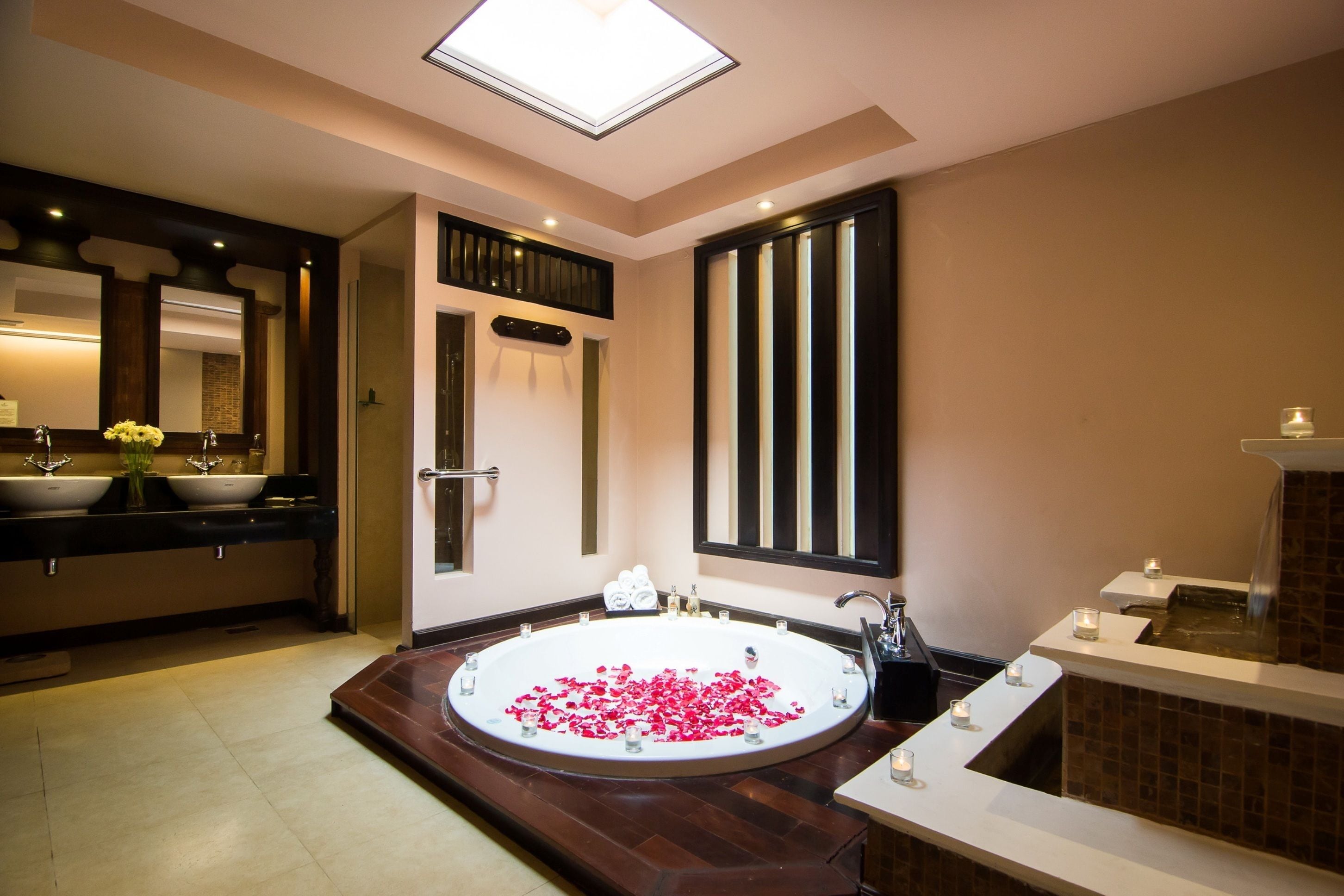A modern bathroom with a large bathtub, a double sink, and a mirror.