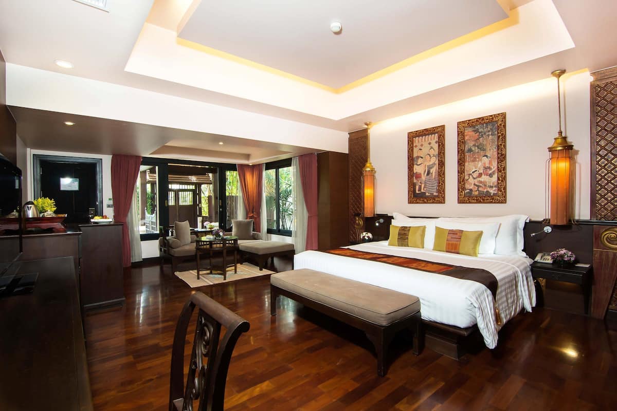 A spacious hotel room with a large bed, a desk, and a seating area.