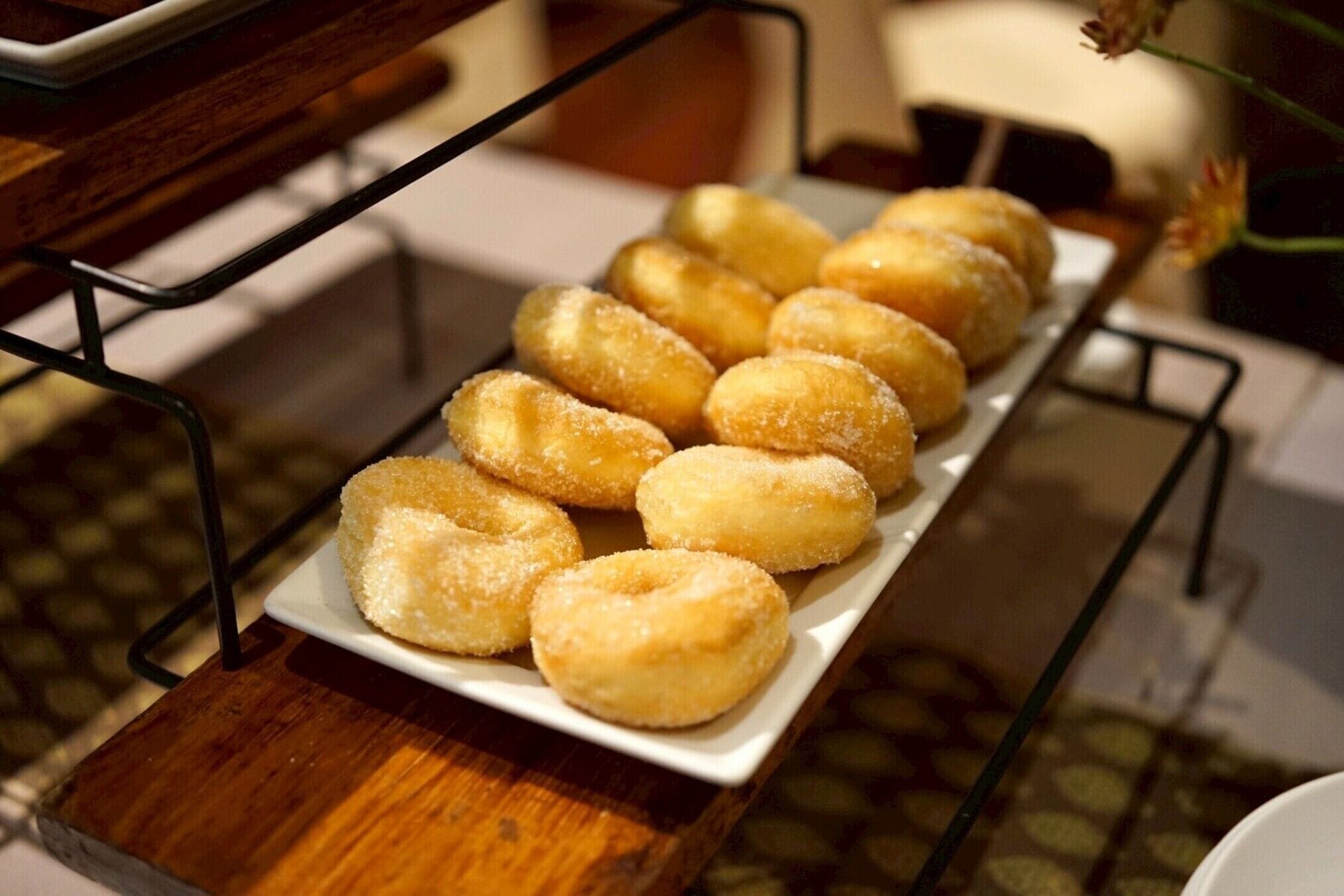 A tray of sugar-coated doughnuts on a white plate.