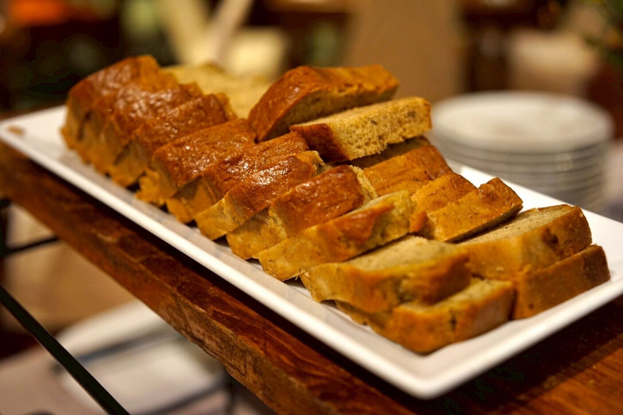 A loaf of bread sliced and arranged on a white plate.