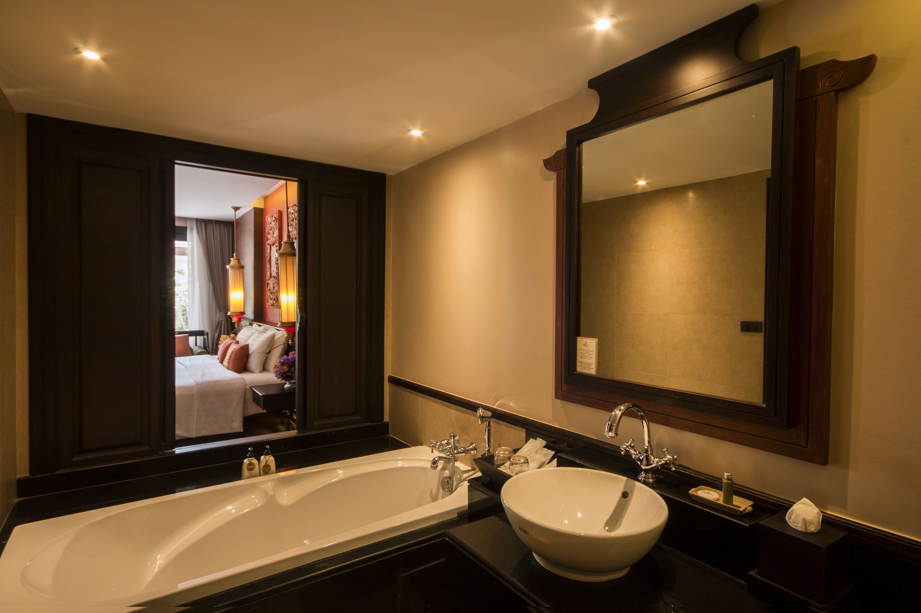 A modern bathroom with a large bathtub, a round sink, and a mirror above the sink.