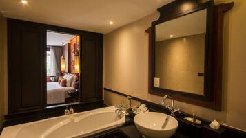 A modern bathroom with a large bathtub, a round sink, and a mirror above the sink.