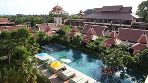 Un resort con piscina rodeada de edificios de estilo tradicional y exuberante vegetación.