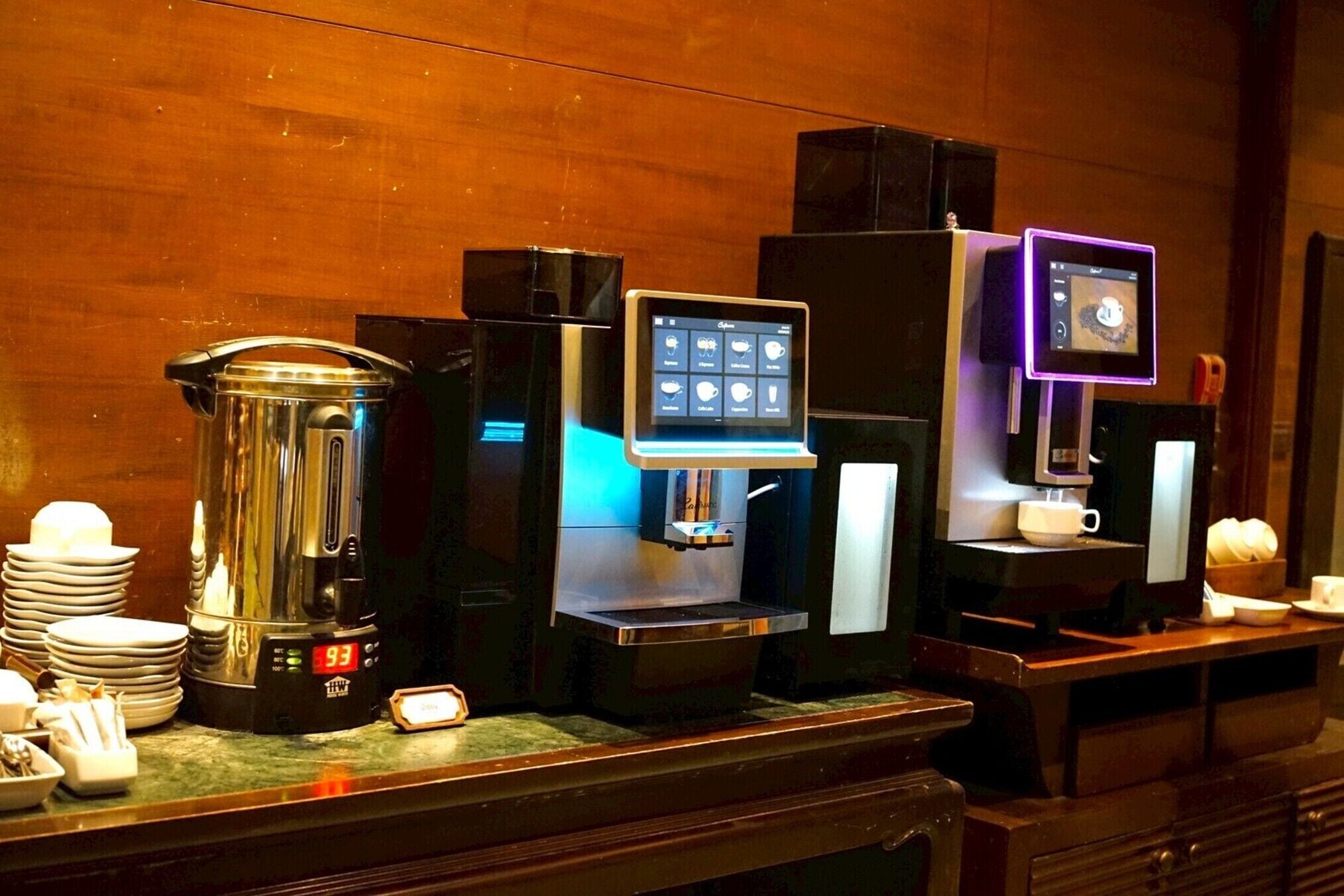 Un espace dédié au café, équipé de plusieurs machines à café, d’une balance et d’une pile d’assiettes.