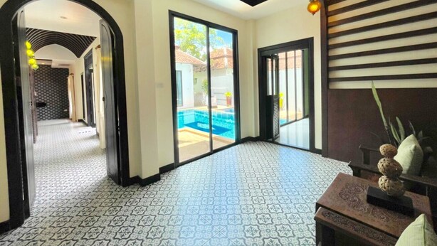 A spacious hallway with patterned floor tiles, a view of a swimming pool, and a door leading to a balcony. - Kana Bay Villa Ao Nang (Krabi)