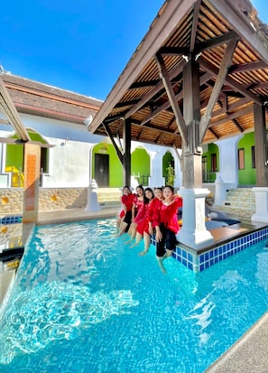 A swimming pool area with a covered seating area and a stone wall. - Kana Bay Villa Ao Nang (Krabi)
