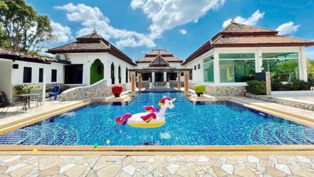 Una piscina con un flotador de unicornio, rodeada de edificios de estilo arquitectónico tradicional.