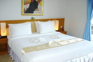 A hotel room with a neatly made bed, a headboard, bedside lamps, and a framed picture on the wall. - Patong Lamai Residence (Patong)