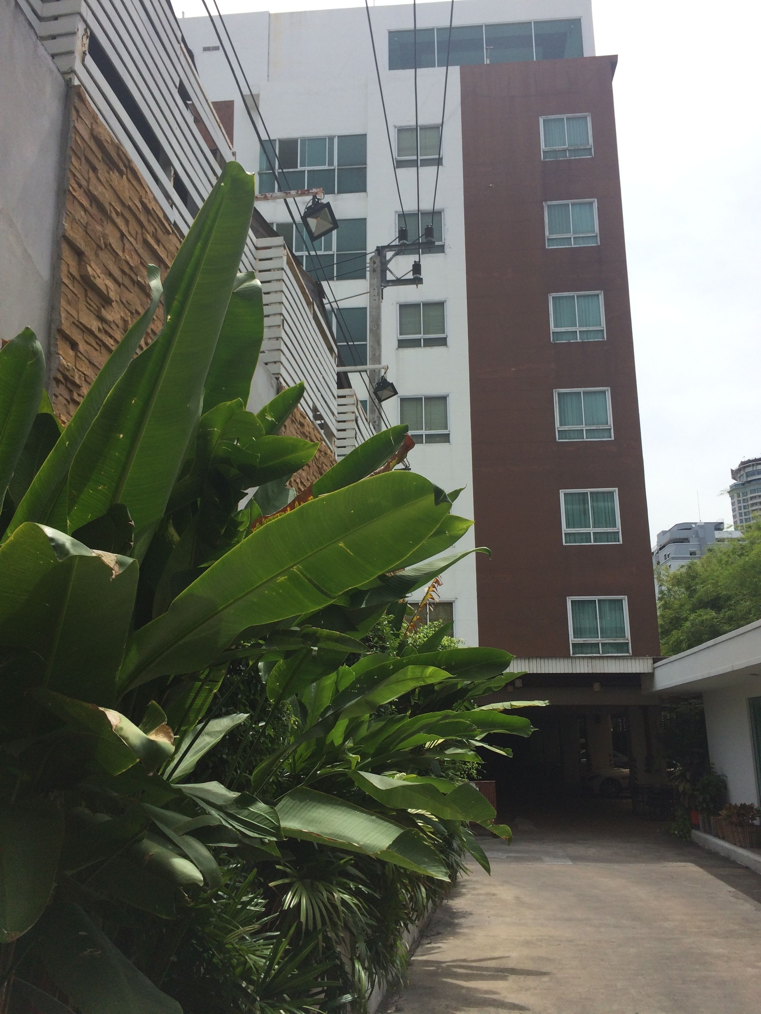 Un edificio de varios pisos con una combinación de fachadas de ladrillo y blanco, ventanas grandes y una entrada visible.