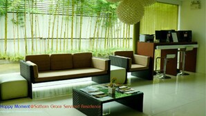 A modern living room with a sofa, coffee table, and a dining area. - Sathorn Grace Serviced Residence (Bangkok)