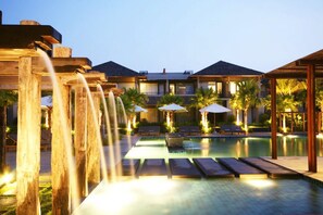 A pool area with wooden structures, lounge chairs, and umbrellas.