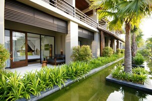 Un hotel moderno con piscina, asientos al aire libre y exuberante vegetación.