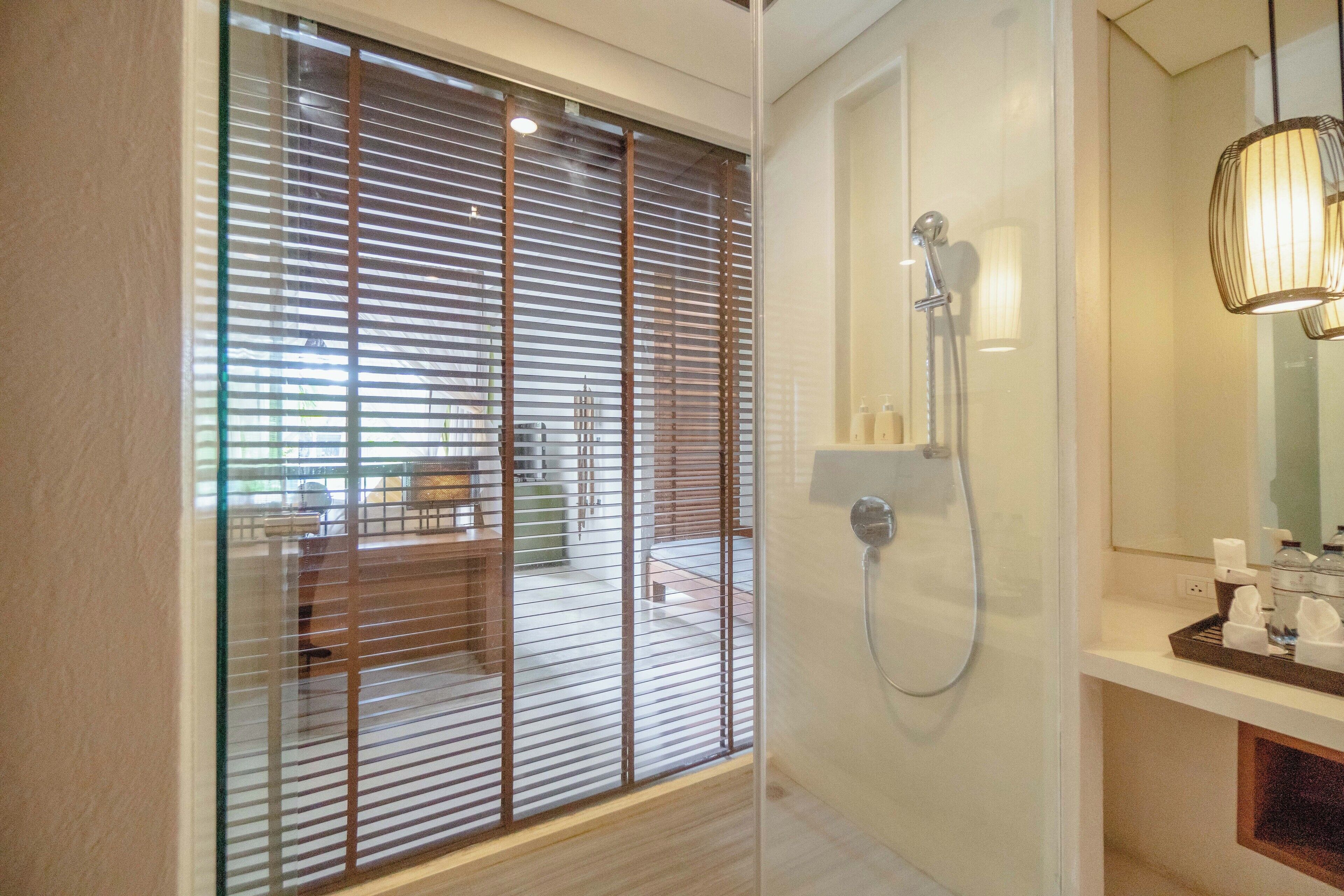 A modern bathroom with a glass door, a shower, and a vanity with toiletries.