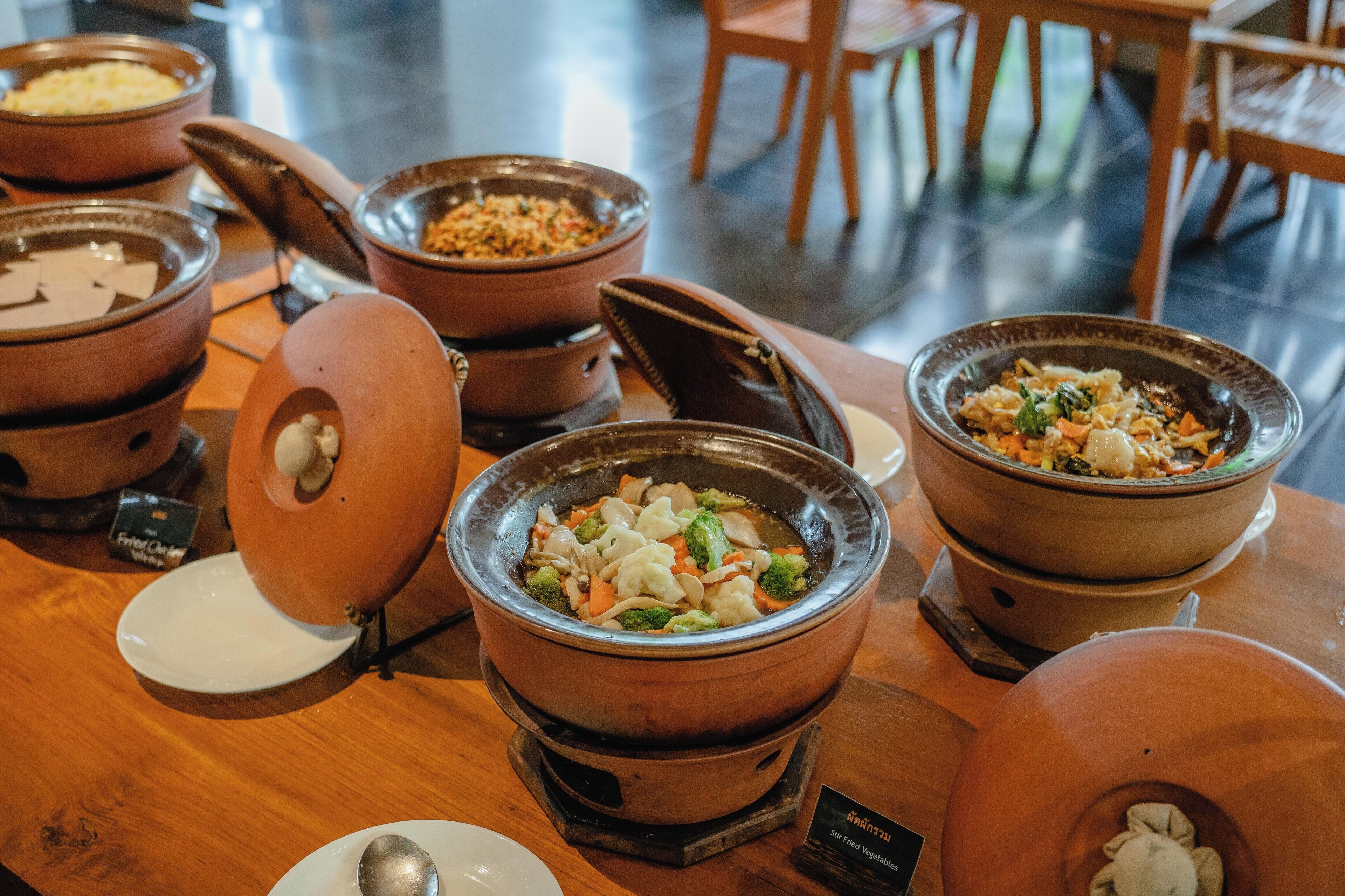 Une table de buffet avec différents plats présentés dans de grands bols en céramique.