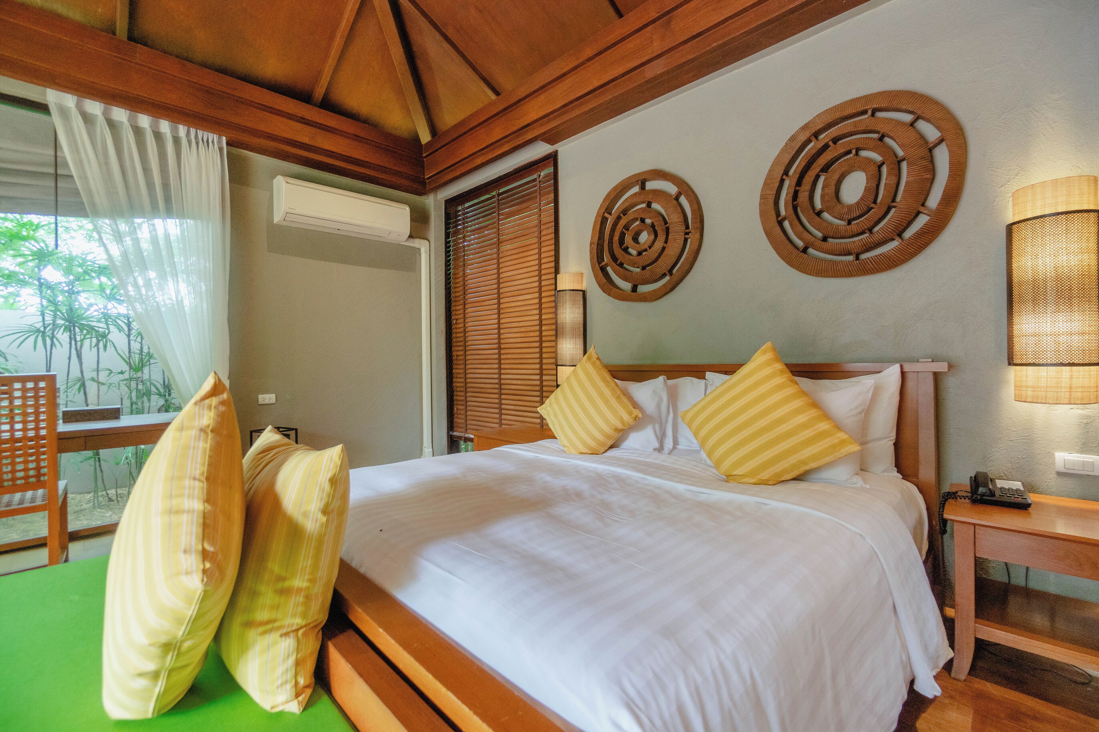 A hotel room with a large bed, wooden headboard, and two wall decor pieces.