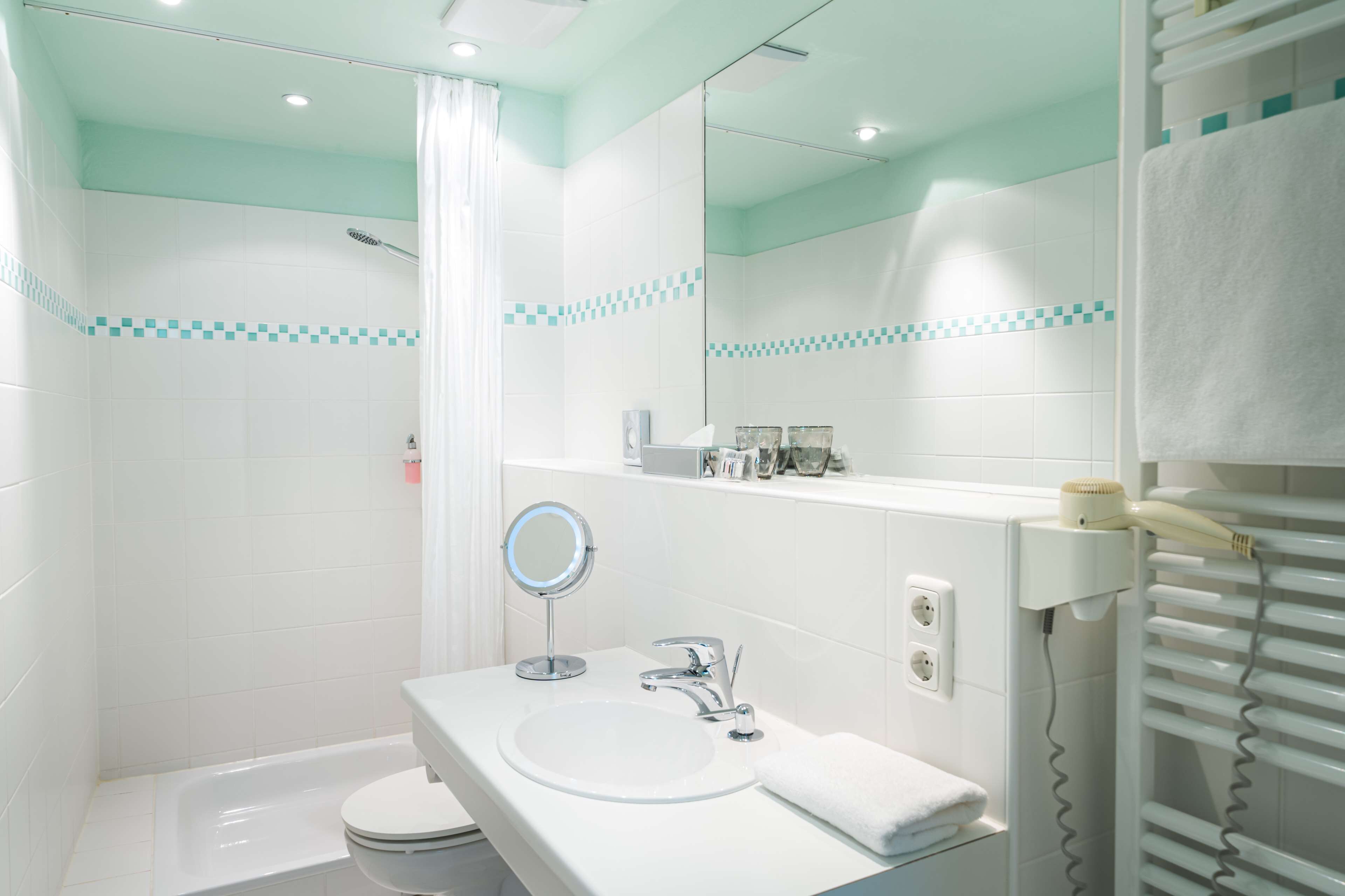 A modern bathroom with a white sink, mirror, and shower.