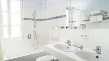 Ein modernes Badezimmer mit einer Badewanne, zwei Waschbecken, einer Toilette und einer Dusche.