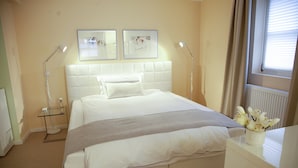 Un dormitorio ordenado con una cama grande, mesitas de noche y un ventanal con cortinas.