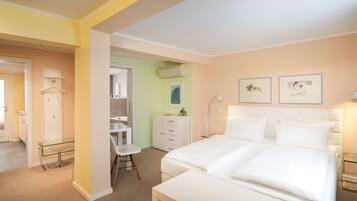 Une chambre d’hôtel avec un grand lit, un bureau, une chaise, une armoire et deux tableaux encadrés au mur.