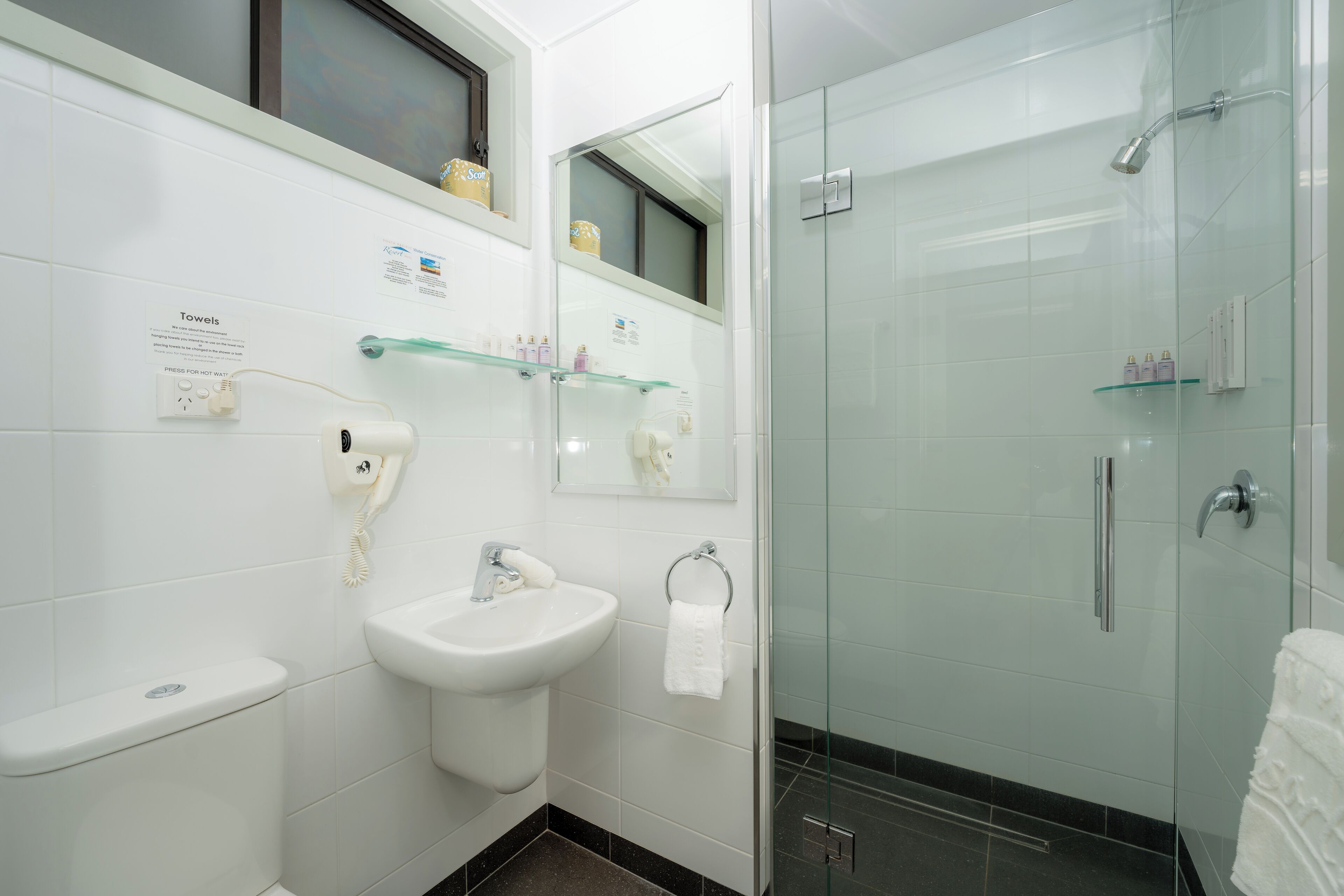 A modern bathroom with a toilet, sink, and glass-enclosed shower.